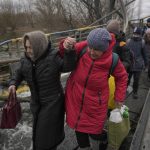 
              Women hold hands while crossing the Irpin river on an improvised path under a bridge that was destroyed by a Russian airstrike, while assisting people fleeing the town of Irpin, Ukraine, Saturday, March 5, 2022. What looked like a breakthrough cease-fire to evacuate residents from two cities in Ukraine quickly fell apart Saturday as Ukrainian officials said shelling had halted the work to remove civilians hours after Russia announced the deal. (AP Photo/Vadim Ghirda)
            