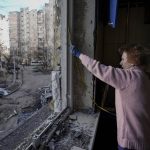 
              A woman measures a window before covering it with plastic sheets in a building damaged by a bombing the previous day in Kyiv, Ukraine, Monday, March 21, 2022. (AP Photo/Vadim Ghirda)
            