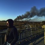 
              A Ukrainian soldier watches as a cloud of smoke raises after an explosion near the airport, in Lviv, western Ukraine, Friday, March 18, 2022. The mayor of Lviv says missiles struck near the city's airport early Friday. (Ismail Coşkun/IHA via AP)
            