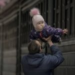 
              A man plays with a child before she boards a Lviv bound train, in Kyiv, Ukraine, Saturday, March 12, 2022. Fighting raged in the outskirts of Ukraine's capital, Kyiv, and Russia kept up its bombardment of other resisting cities. (AP Photo/Vadim Ghirda)
            