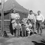 FILE - The Theodore James family lives in a 16-foot square tent outside the city of Tulare, in California's San Joaquin valley, shown March 22, 1950.  Genealogists and historians can get a microscopic look at sweeping historical trends when individual records from the 1950 census are released this week. Researchers view the records that will be released Friday, March 31, 2022 as a gold mine, and amateur genealogists see it as a way to fill gaps in family trees.  (AP Photo/David F. Smith, File)