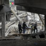 
              Ukrainian soldiers carry a body of a civilian killed by the Russian forces under the destroyed bridge in Irpin close to Kyiv, Ukraine, Thursday, March 31, 2022. The more than month-old war has killed thousands and driven more than 10 million Ukrainians from their homes including almost 4 million from their country. (AP Photo/Efrem Lukatsky)
            