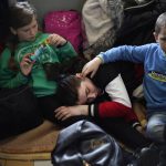 
              A woman and two children, who have fled Ukraine, take rest in the lobby of the train station in Przemysl, Poland, Sunday, March 13, 2022. Now in its third week, the war has forced more than 2.5 million people to flee Ukraine. (AP Photo/Daniel Cole)
            