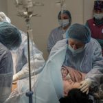 
              FILE - Medical workers hold newborn Alana close to her mother after a cesarean section at a hospital in Mariupol, Ukraine, March 11, 2022. Alana's mother had to be evacuated from another maternity hospital that was bombed by Russian forces and lost some of her toes. (AP Photo/Evgeniy Maloletka, File)
            