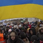 
              A Ukrainian volunteer Oleksandr Osetynskyi, 44 holds a Ukrainian flag and directs hundreds of refugees after fleeing from the Ukraine and arriving at the border crossing in Medyka, Poland, Monday, March 7, 2022. Russia announced yet another cease-fire and a handful of humanitarian corridors to allow civilians to flee Ukraine. Previous such measures have fallen apart and Moscow’s armed forces continued to pummel some Ukrainian cities with rockets Monday. (AP Photo/Visar Kryeziu)
            