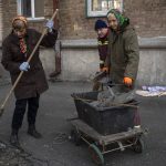 
              Residents clean the street outside apartments damaged by shelling, in Kyiv, Ukraine,Wednesday, March 23, 2022. (AP Photo/ (AP Photo/Rodrigo Abd)
            