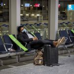 
              A passenger rests in a terminal at the airport during a one day strike of security employees who control the flow of passengers and luggage in Frankfurt, Germany, Tuesday, March 15, 2022. (AP Photo/Michael Probst)
            