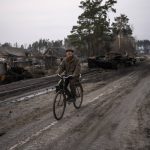 
              Oleksandr, 81, rides a bicycle next to a destroyed Russian tank in the outskirts of Kyiv, Ukraine, Thursday, March 31, 2022. Russian forces shelled Kyiv suburbs, two days after the Kremlin announced it would significantly scale back operations near both the capital and the northern city of Chernihiv to “increase mutual trust and create conditions for further negotiations.”  (AP Photo/Rodrigo Abd)
            