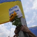 
              A protest holds up a sunflower and a sign with a message that reads in Spanish: "Putin Killer", during a protest against Russian's invasion of the Ukraine, outside of the European Union offices, in Caracas, Venezuela, Thursday, March 3, 2022. (AP Photo/Ariana Cubillos)
            