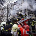 
              In this photo released by Ukrainian State Emergency Service press service, firefighters evacuate a man from an apartment building hit by shelling in Kyiv, Ukraine, Monday, March 14, 2022. (Ukrainian State Emergency Service via AP)
            