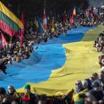 
              People carry a giant Ukrainian flag to protest against the Russian invasion of Ukraine during a celebration of Lithuania's independence in Vilnius, Lithuania, Friday, March 11, 2022. Lithuania celebrated the 32th anniversary of its declaration of independence from the Soviet Union on Friday, recalling the seminal events that set the Baltic nation on a path to freedom and helped lead to the collapse of the U.S.S.R. (AP Photo/Mindaugas Kulbis)
            