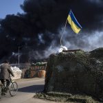 
              A man rides a bicycle as black smoke rises from a fuel storage of the Ukrainian army following a Russian attack, on the outskirts of Kyiv, Ukraine, Friday, March 25, 2022. (AP Photo/ (AP Photo/Rodrigo Abd)
            