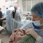 
              A medical worker holds a newborn girl, Alana, after cesarian section in a hospital in Mariupol, Ukraine, Friday, March 11, 2022. Alana's mother had to be evacuated from another maternity hospital and lost some of her toes after it was shelled. (AP Photo/Evgeniy Maloletka)
            