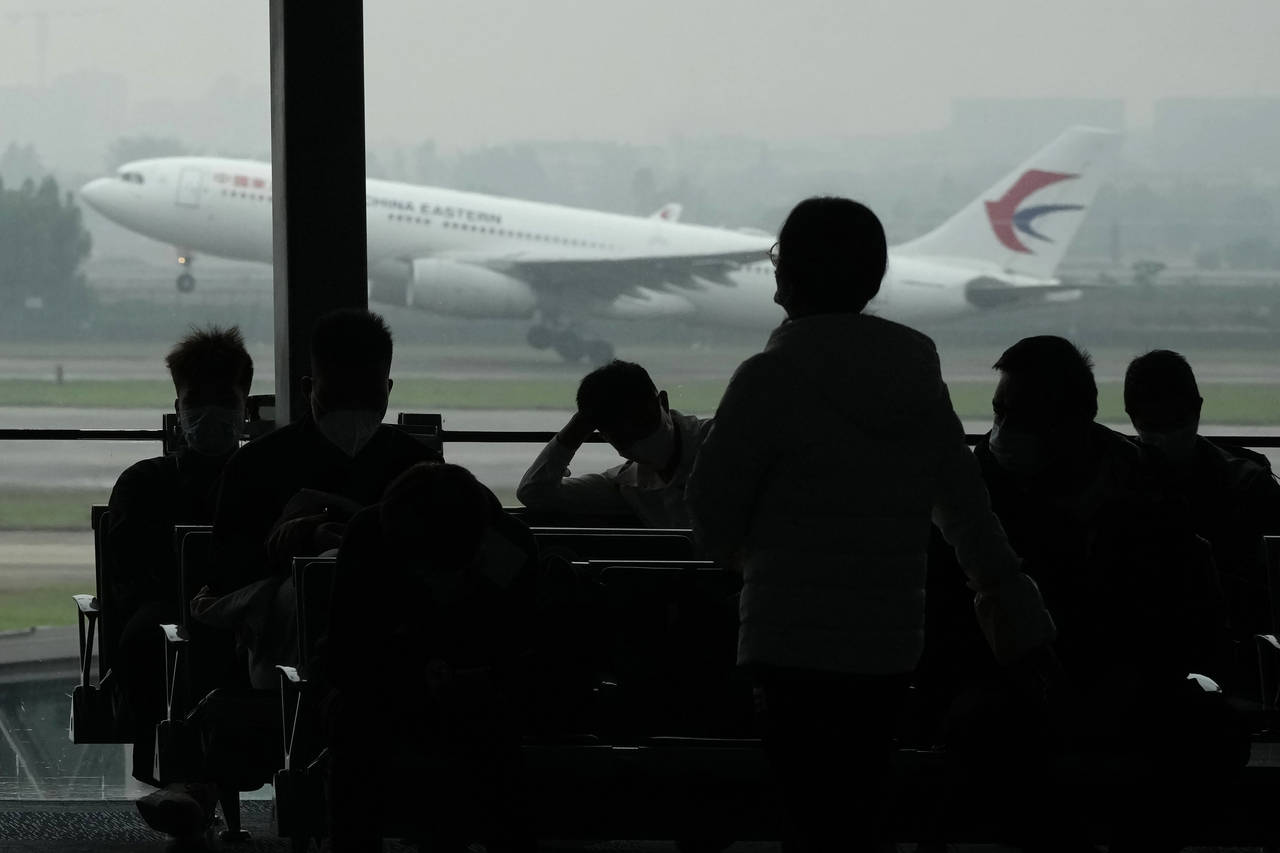Passengers wait for their flight as a China Eastern flight takes off from the runway of Baiyun Airp...