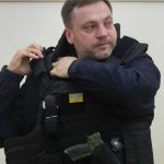 
              Ukrainian Interior Minister Denys Monastyrsky puts on a bulletproof vest after his interview with The Associated Press in his office in Kyiv, Ukraine, Friday, March 18, 2022. Monastyrsky said that it will take years to defuse the unexploded ordnance once the Russian invasion is over. (AP Photo/Efrem Lukatsky)
            