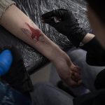 
              Ukrainian Natalia Tanchynets works on a patriotic-themed tattoo at her workshop in Lviv, Western Ukraine, Saturday, March 19, 2022. Fighting raged on multiple fronts in Ukraine more than three weeks after Russia's Feb. 24 invasion. U.N. bodies have confirmed more than 800 civilian deaths since the war began but say the real toll is considerably higher. The U.N. says more than 3.3 million people have fled Ukraine as refugees. (AP Photo/Bernat Armangue)
            