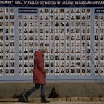 
              A woman walks by a memorial wall for those who lost their lives since the beginning of the conflict in Eastern Ukraine in Kyiv, Ukraine, Friday, March 18, 2022. Residents of the Ukrainian capital of Kyiv on took to a central square to arrange some 1.5 million tulips in the shape of the country's coat of arms, in a defiant show of normalcy as Russian forces surround and bomb the city. (AP Photo/Vadim Ghirda)
            