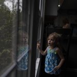
              Alyssa Carpenter, 2, looks out of a window of her home in Haymarket, Va., Friday, Jan. 28, 2022. Alyssa has had COVID-19 twice and suffers long-term symptoms. She is part of a NIH-funded multi-year study at Children's National Hospital to look at impacts of COVID-19 on children's physical health and quality of life. (AP Photo/Carolyn Kaster)
            