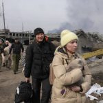 
              A woman carries her cat near a destroyed bridge as she flees from her hometown on the road towards Kyiv, in the town of Irpin, some 25 km (16 miles) northwest of Kyiv, Saturday, March 12, 2022. Kyiv northwest suburbs such as Irpin and Bucha have been enduring Russian shellfire and bombardments for over a week prompting residents to leave their home. (AP Photo/Efrem Lukatsky)
            