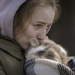 
              A woman who was evacuated from Irpin cries kissing a cat wrapped in a blanket at a triage point in Kyiv, Ukraine, Friday, March 11, 2022. A large scale evacuation operation of residents of a satellite area of capital Kyiv continued Friday, with more and more people deciding to leave areas now under Russian control. (AP Photo/Vadim Ghirda)
            