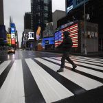 
              FILE - A man crosses the street in a nearly empty Times Square, which is usually very crowded on a weekday morning in New York on March 23, 2020. (AP Photo/Mark Lennihan, File)
            