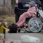 
              FILE - A wheelchair user that fled the conflict from neighbouring Ukraine await transportation at the Romanian-Ukrainian border, in Siret, Romania, Sunday, Feb. 27, 2022. The United Nations says that more than 3.6 million people have fled Ukraine since the war started exactly one month ago Thursday in what is the biggest movement of people in Europe since World War II. Unprepared, most refugees believed they would soon be back home. That hope is waning now. (AP Photo/Andreea Alexandru, File)
            