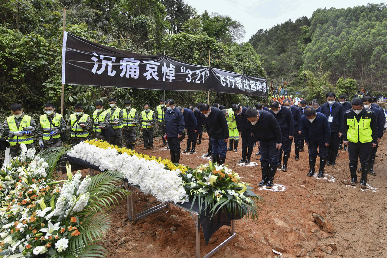 In this photo released by Xinhua News Agency, officials and search and rescue workers bow and pause...