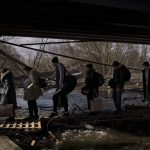 
              Ukrainians cross an improvised path under a destroyed bridge while fleeing Irpin, on the outskirts of Kyiv, Ukraine, Wednesday, March 9, 2022. (AP Photo/Felipe Dana)
            