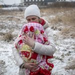 
              Axana Opalenko, 42, holds Meron, 2 months old, in an effort to warm him after fleeing from Ukraine, at the border crossing in Medyka, Poland, Wednesday, March 9, 2022. U.N. officials said that the Russian onslaught has forced 2 million people to flee Ukraine. It has trapped others inside besieged cities that are running low on food, water and medicine amid the biggest ground war in Europe since World War II. (AP Photo/Visar Kryeziu)
            