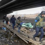 
              Ukrainians soldiers pass an improvised path under a destroyed bridge as they evacuate an elderly resident in Irpin, northwest of Kyiv, Saturday, March 12, 2022. Kyiv northwest suburbs such as Irpin and Bucha have been enduring Russian shellfire and bombardments for over a week prompting residents to leave their home. (AP Photo/Efrem Lukatsky)
            