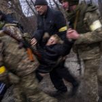 
              A sick woman is carried in semi-conscious by Ukrainian soldiers as they cross the Irpin river as fleeing the city in the outskirts of Kyiv, Ukraine, Saturday, March 5, 2022. (AP Photo/Emilio Morenatti)
            