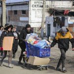 
              Local residents carry water from the food warehouse, on the territory which is under the Government of the Donetsk People's Republic control, on the outskirts of Mariupol, Ukraine, Friday, March 18, 2022. (AP Photo/Alexei Alexandrov)
            