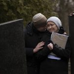 
              Oksana his hugged by her soon Dmytro during the funeral of her husband Volodymyr Nezhenets, 54, in the city of Kyiv, Ukraine, Friday, March 4, 2022. A small group of reservists are burying their comrade, 54-year-old Volodymyr Nezhenets, who was one of three killed on  Feb. 26 in an ambush Ukrainian authorities say was caused by Russian 'saboteurs'. (AP Photo/Emilio Morenatti)
            