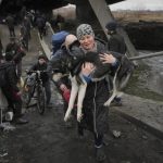 
              A woman holds a dog while crossing the Irpin river on an improvised path under a bridge that was destroyed by a Russian airstrike, while assisting people fleeing the town of Irpin, Ukraine, Saturday, March 5, 2022. What looked like a breakthrough cease-fire to evacuate residents from two cities in Ukraine quickly fell apart Saturday as Ukrainian officials said shelling had halted the work to remove civilians hours after Russia announced the deal. (AP Photo/Vadim Ghirda)
            