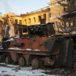 
              A destroyed armored personnel carrier stands in front of a damaged by shelling building in Kharkiv, Ukraine, Friday, March 11, 2022. (AP Photo/Andrew Marienko)
            