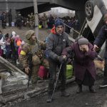 
              An elderly lady is assisted while crossing the Irpin river, under a bridge that was destroyed by a Russian airstrike, as civilians flee the town of Irpin, Ukraine, Saturday, March 5, 2022. What looked like a breakthrough cease-fire to evacuate residents from two cities in Ukraine quickly fell apart Saturday as Ukrainian officials said shelling had halted the work to remove civilians hours after Russia announced the deal. (AP Photo/Vadim Ghirda)
            