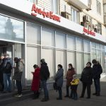 
              People stand in line to withdraw money from an ATM of Alfa Bank in Moscow, Russia, Sunday, Feb. 27, 2022. Russians flocked to banks and ATMs shortly after Russia launched an attack on Ukraine and the West announced crippling sanctions. (AP Photo)
            