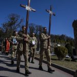 
              Ukrainian soldiers prepare to bury 32-year-old Senior Lieutenant Pavlo Chernikov, in the photograph at left, and 47-year-old soldier Roman Valkov, during their funeral ceremony, after being killed in action, at the Lychakiv cemetery, in Lviv, western Ukraine, Monday, March 28, 2022. The more than month-old war has killed thousands and driven more than 10 million Ukrainians from their homes — including almost 4 million from their country. (AP Photo/Nariman El-Mofty)
            
