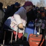 
              A woman waits in a line to board the train to get back to Ukraine at a railway station in Przemysl, Poland, on Tuesday, March 22, 2022. People from Ukraine could cross the border several times to help with evacuation for refugees, mostly for children. (AP Photo/Sergei Grits)
            