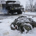 
              The body of a serviceman is coated in snow next to a destroyed Russian military multiple rocket launcher vehicle on the outskirts of Kharkiv, Ukraine, Friday, Feb. 25, 2022. Russian troops bore down on Ukraine's capital Friday, with gunfire and explosions resonating ever closer to the government quarter, in an invasion of a democratic country that has fueled fears of wider war in Europe and triggered worldwide efforts to make Russia stop. (AP Photo/Vadim Ghirda)
            