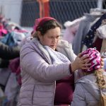 
              A woman fits a hat from a rack of clothes onto a small girl on the border in Vysne Nemecke, Slovakia, Thursday, March 3, 2022. More than 1 million people have fled Ukraine following Russia's invasion in the swiftest refugee exodus in this century, the United Nations said Thursday. (AP Photo/Darko Vojinovic)
            