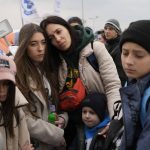 
              Refugees wait in a queue, after fleeing the war from neighbouring Ukraine at the border crossing in Medyka, southeastern Poland, on Tuesday, March 29, 2022. The daily number of people fleeing Ukraine has fallen in recent days but border guards, aid agencies and refugees say Russia's unpredictable war offers few signs whether it's just a temporary lull or a permanent drop-off. (AP Photo/Sergei Grits)
            