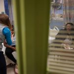 
              Brooklynn Chiles, 8, is examined during a followup visit at Children's National Hospital in Washington, Friday, Feb. 11, 2022, as her mother, Danielle Mitchell watches at right. Brooklynn's father, Rodney Chiles, died of COVID-19 last year and she has tested positive three times. Brooklynn is part of a NIH-funded multi-year study at Children's National Hospital to look at impacts of COVID-19 on children's physical health and quality of life. (AP Photo/Carolyn Kaster)
            