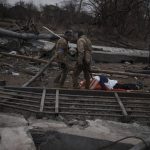 
              The body of a civilian, whose cause of death is unknown, lays on a stretcher on a path being used as an evacuation route out of Irpin, on the outskirts of Kyiv, Ukraine, Saturday, March 12, 2022. Kyiv northwest suburbs such as Irpin and Bucha have been enduring Russian shellfire and bombardments for over a week prompting residents to leave their homes. (AP Photo/Felipe Dana)
            
