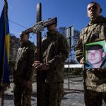 
              A Ukrainian soldier holds the photograph of 47-year-old soldier Roman Valkov, during his funeral ceremony, after being killed in action, at the Holy Apostles Peter and Paul Church in Lviv, western Ukraine, Monday, March 28, 2022. The more than month-old war has killed thousands and driven more than 10 million Ukrainians from their homes — including almost 4 million from their country. (AP Photo/Nariman El-Mofty)
            