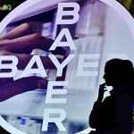 
              FILE - A woman walks in front of a logo of Bayer AG at the Financial News Conference in Leverkusen, Germany, Feb. 27, 2020. Ukrainian President Volodymyr Zelenskyy is stepping up the country's pleas to pressure companies to exit Russia. On Tuesday, March 15, 2022, in an address, Zelenskyy called out food companies Nestle and Mondelez, consumer goods makers Unilever and Johnson & Johnson, and pharmaceuticals Bayer and Sanofi, saying they and “dozens of other companies” have not left the Russian market. Companies, in turn, point to the difficulties of ceasing operations. (AP Photo/Martin Meissner, File)
            