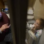 
              Lexie Stroiney, 6, looks to respiratory therapist Tm Murray from inside the plethysmography chamber during a pulmonary function test at Children's National Hospital, in Washington, Wednesday, Jan. 26, 2022. Lexie had COVID-19 and is part of a NIH-funded multi-year study at Children's National Hospital to look at impacts of COVID-19 on children's physical health and quality of life. (AP Photo/Carolyn Kaster)
            