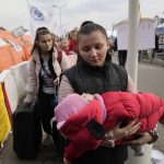 
              A refugee carries a baby after fleeing the war from neighbouring Ukraine at the border crossing in Medyka, southeastern Poland, on Tuesday, March 29, 2022. The daily number of people fleeing Ukraine has fallen in recent days but border guards, aid agencies and refugees say Russia's unpredictable war offers few signs whether it's just a temporary lull or a permanent drop-off. (AP Photo/Sergei Grits)
            
