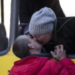 
              Mykolaivna Shankarukina, 54, kisses her son from inside a damaged bus as she is leaving from the Ukrainian Red Cross center in Mykolaiv, southern Ukraine, on Monday, March 28, 2022. Shankarukina and her family evacuated from Sablagodante village at Mykolaiv district that have been attacked by the Russian army. She and her grandson go to Odesa and from there to Prague, as the rest of the family (son, daughter in law and little grandson) will stay in Mykolaiv in a center for displaced residents. (AP Photo/Petros Giannakouris)
            