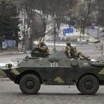 
              Ukrainian servicemen ride on top of an armored personnel carrier speeding down a deserted boulevard during an air raid alarm, in Kyiv, Ukraine, Tuesday, March 1, 2022. The U.N.'s refugees chief is warning that many more vulnerable people will begin fleeing their homes in Ukraine if Russia's military offensive continues and further urban areas are hit. (AP Photo/Vadim Ghirda)
            